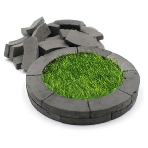 Puede incluir: Un macetero circular hecho de baldosas de hormigón gris con un lecho de césped artificial verde en su interior.