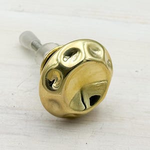 May include: A gold-coloured, textured cabinet knob with a silver screw. The knob has an irregular, organic shape with a hammered appearance. The design is modern and decorative, suitable for furniture upgrades.