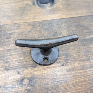 K&ouml;nnte beinhalten: Schwarzer Metall-Klampenhaken, ein nautischer Haken mit abgerundeter Basis und gebogenem Oberteil, perfekt zum Aufh&auml;ngen von Gegenst&auml;nden in einem K&uuml;sten-Haus.