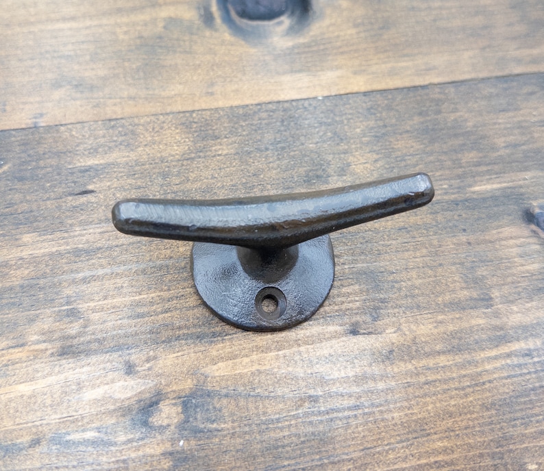 K&ouml;nnte beinhalten: Schwarzer Metall-Klampenhaken, ein nautischer Haken mit abgerundeter Basis und gebogenem Oberteil, perfekt zum Aufh&auml;ngen von Gegenst&auml;nden in einem K&uuml;sten-Haus.