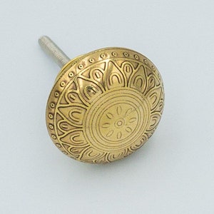 Peut inclure: Un bouton de porte en métal doré avec un motif floral circulaire détaillé.