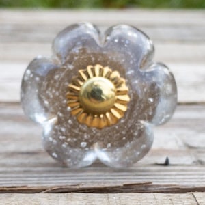 May include: A clear glass flower-shaped cabinet knob with a gold metal centre.