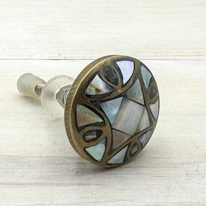 May include: A round brass cabinet knob with a decorative inlay of iridescent mother-of-pearl tiles.