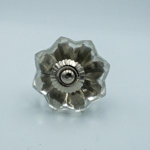 以下が含まれることがあります： 星形のデザインと銀色の金属製のベースを持つ透明なガラス製のキャビネットノブです。