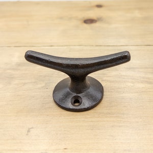 K&ouml;nnte beinhalten: Schwarzer Bootshaken aus Gusseisen, ein nautischer Wandhaken mit gebogenem Arm und runder Basis.