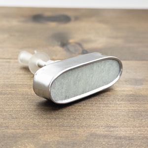 May include: A silver oval cabinet knob with a white marble insert. The knob has a screw on the back for installation.