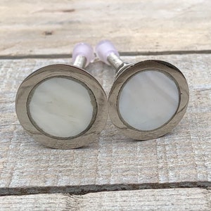 Peut inclure: Deux boutons ronds de cabinet en argent et blanc avec un incrustation de nacre.
