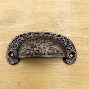 May include: A black cast iron drawer pull with a decorative floral design.