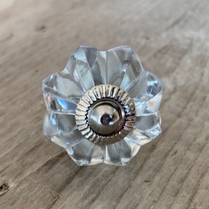 Peut inclure: Un bouton de porte en verre transparent avec un centre en métal argenté. Le bouton a un design cannelé et est parfait pour ajouter une touche d'élégance à n'importe quelle porte.