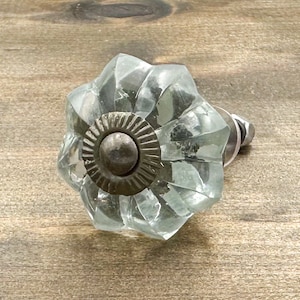 May include: A clear glass cabinet knob with a starburst design and a silver metal base.