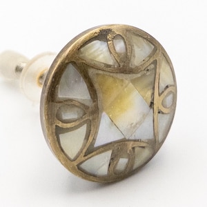 May include: A round brass knob with a decorative design featuring a white and gold mother of pearl inlay.