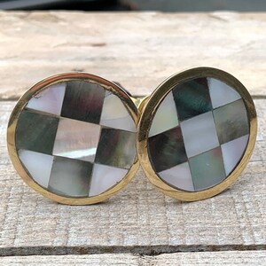May include: Two round brass cabinet knobs with a checkered pattern of white and black mother of pearl inlay.