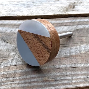 Peut inclure: Un bouton rond en bois avec un motif géométrique blanc et bois. Le bouton a une vis en métal argenté.