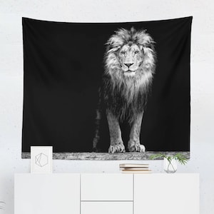 May include: Black and white tapestry featuring a majestic lion. The lion is centered, with a full mane and intense gaze. The background is solid black, emphasizing the lion's presence. The tapestry is likely made of fabric and is designed for wall decor.