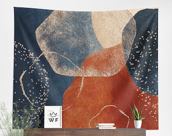 May include: Abstract wall tapestry featuring large, organic shapes in shades of blue, orange, and beige with gold glitter accents. The tapestry is hanging on a white wall above a wooden console table.