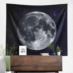 Puede incluir: Un tapiz en blanco y negro con una gran luna llena sobre un cielo oscuro y estrellado. La luna tiene una superficie detallada y texturizada.