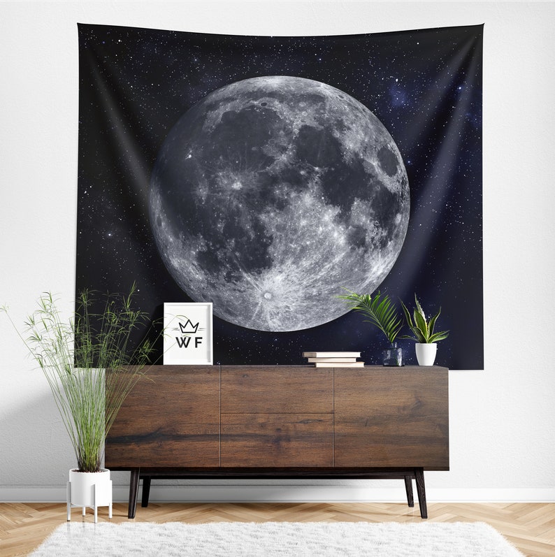 Puede incluir: Un tapiz en blanco y negro con una gran luna llena sobre un cielo oscuro y estrellado. La luna tiene una superficie detallada y texturizada.