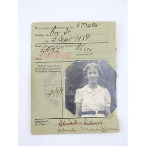 May include: Aged registration certificate from 1939, with a black and white photograph of a woman. The document shows signs of wear, with handwritten details and a stamp. The text includes the name Martignoni and the date of issue.