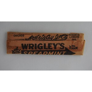 May include: Vintage Wrigley's Spearmint gum package. The brown paper wrapper features black text that reads "Wrigley's Spearmint" and "The Flavor". The package also includes the Wrigley's logo and the text "Chicago, New York, Toronto, London, Eng."