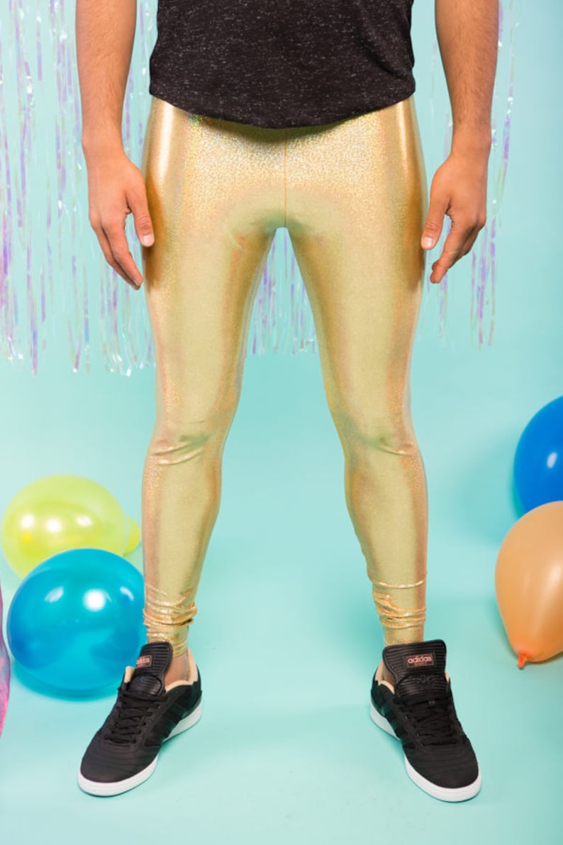 May include: Gold metallic leggings with a subtle iridescent sheen. The leggings are worn by a person standing on a light blue background with balloons.