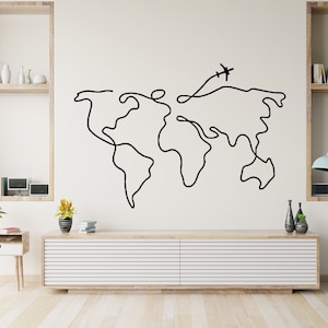 May include: A black and white line drawing of a world map with a small airplane flying above it. The map is on a white wall above a light wood cabinet with a light wood top.