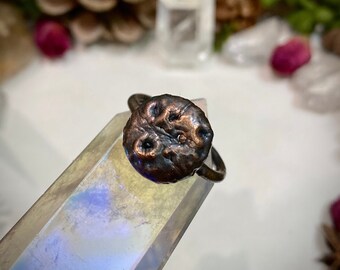May include: A rustic copper ring with a textured, hammered finish. The ring is a unique and earthy piece of jewelry.