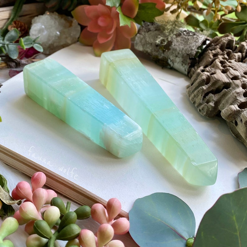 Puede incluir: Dos varitas de cristal rayadas de color azul claro y verde, tambi&eacute;n conocidas como puntas, sobre una superficie blanca. Las varitas miden aproximadamente 15 cm de largo.