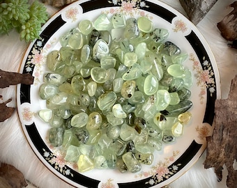 Puede incluir: Primer plano de un plato lleno de piedras pulidas verdes y negras. Las piedras son lisas y pulidas, y tienen una variedad de formas y tamaños.
