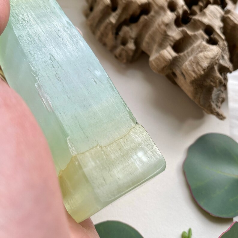 Puede incluir: Un cristal de color verde p&aacute;lido y blanco con una superficie lisa y pulida. El cristal tiene una l&iacute;nea natural que lo atraviesa, lo que a&ntilde;ade a su car&aacute;cter &uacute;nico.