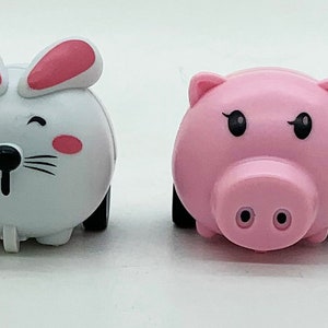 May include: A line of six toy cars, each shaped like a different animal: a monkey, tiger, rabbit, pig, cow, and giraffe. The toys are brightly coloured and have black wheels. Each animal has a cartoon-like design.