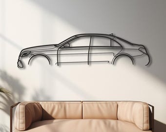 Puede incluir: Arte mural de metal negro con contorno de coche. La obra de arte está montada en una pared blanca sobre un sofá beige. La habitación tiene suelo de madera, una ventana grande y plantas en macetas.