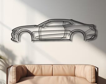 Puede incluir: Una pieza de arte mural de metal negro que representa el perfil lateral de un coche, montada en una pared blanca. El contorno del coche no tiene ruedas. Un sofá marrón claro se encuentra debajo de la obra de arte, con plantas en macetas a ambos lados.