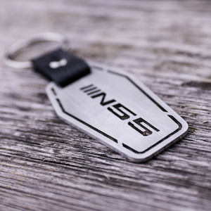 May include: A silver metal keychain with a black leather strap and the word "IN55" engraved on it.