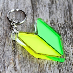 May include: A green and yellow plastic keychain shaped like a Japanese beginner's mark, also known as a "beginner's mark".