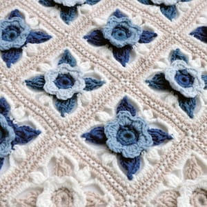 May include: A crocheted blanket featuring a repeating pattern of blue and white flowers. The blanket is crafted with a delicate, lacy stitch.