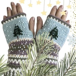 Puede incluir: Un par de guantes sin dedos azules y blancos con un diseño de ganchillo que presenta un pequeño árbol verde y cuentas blancas. Los guantes están hechos con un hilo texturizado y tienen un puño marrón y blanco.