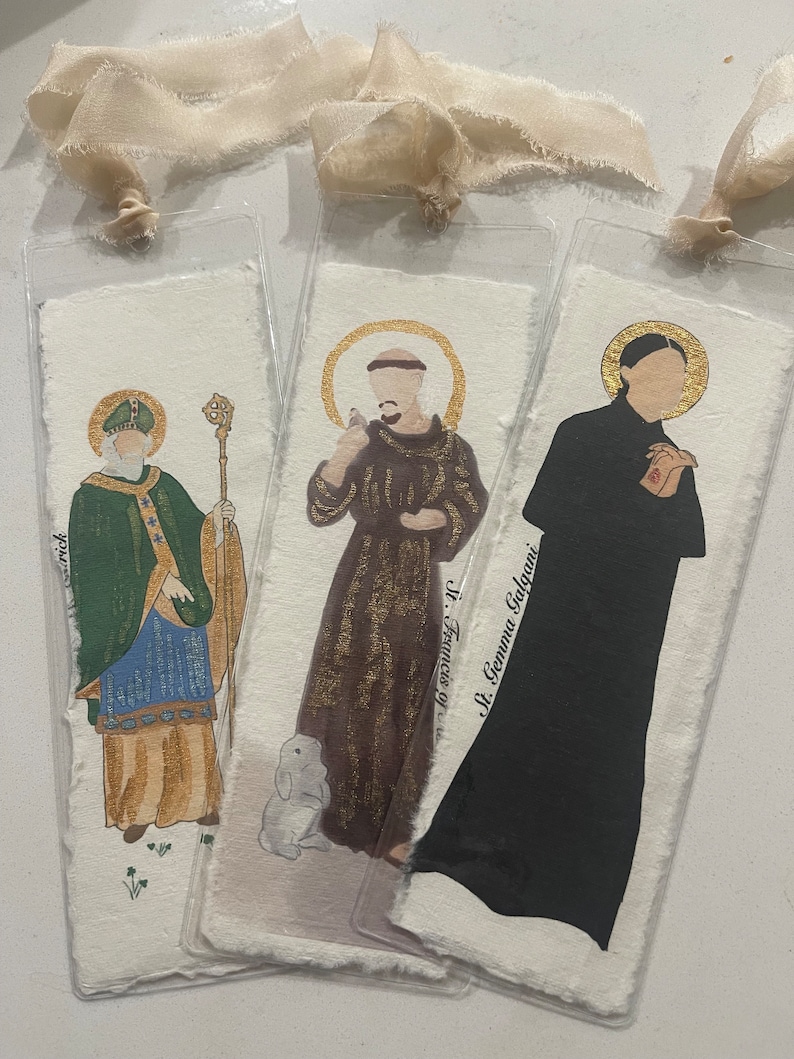 Puede incluir: Tres marcadores ilustrados con figuras religiosas. El primer marcador presenta a San Patricio con ropas verdes sosteniendo un bast&oacute;n. El segundo marcador presenta a San Francisco de As&iacute;s con ropas marrones sosteniendo un p&aacute;jaro. El tercer marcador presenta a Santa Gemma Galgani con un h&aacute;bito negro con las manos juntas en oraci&oacute;n.