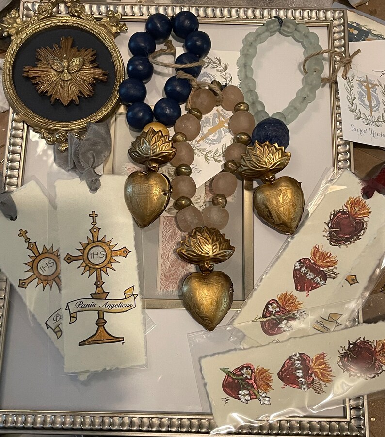 Puede incluir: Una colecci&oacute;n de artesan&iacute;as y decoraciones de tem&aacute;tica religiosa, que incluye un coraz&oacute;n dorado con una cruz, una imagen enmarcada de una estrella dorada y varios marcadores con im&aacute;genes religiosas. Los art&iacute;culos est&aacute;n dispuestos sobre una superficie blanca con un marco decorativo.