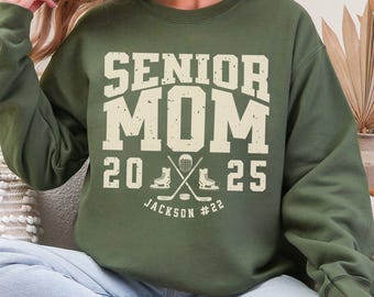 May include: A green sweatshirt with the text "Senior Mom 2025 Jackson #22" and a hockey stick and skate graphic.