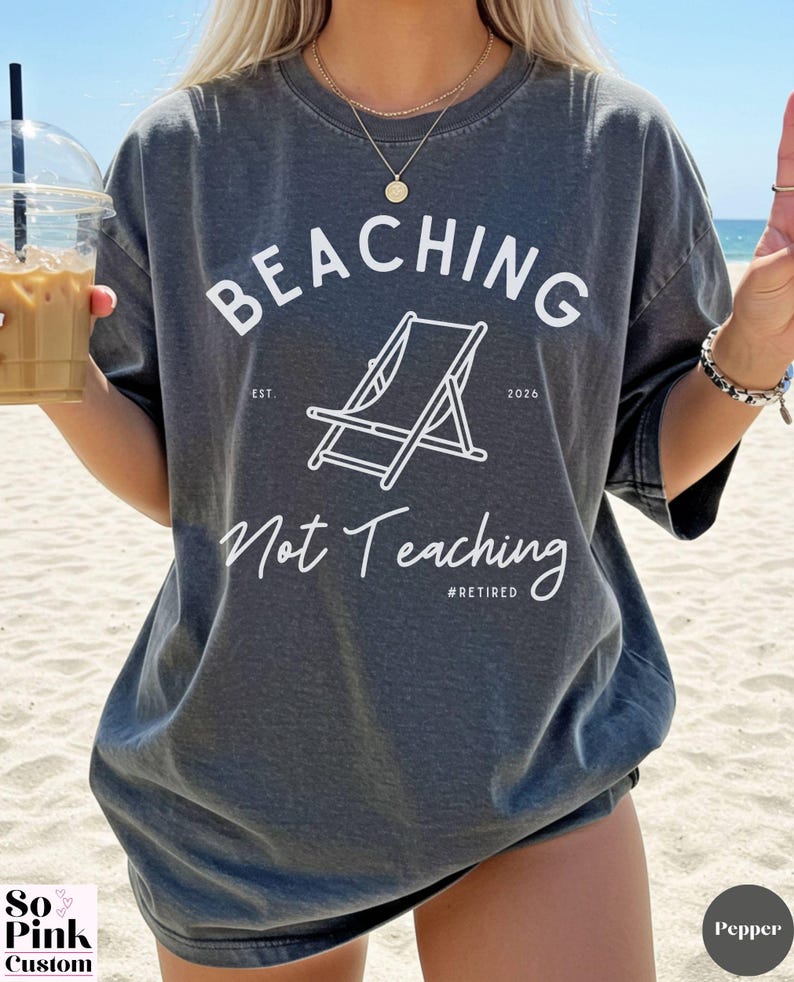 Comfort Colors Shirt with deck chair illustration in the center, curved text above, script below - BEACHING Not Teaching #Retired Year Est. 2026