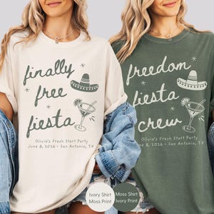 May include: Two short-sleeve crewneck t-shirts, one ivory with dark green text and one moss green with ivory text. Both feature a sombrero, a cocktail glass, and the text "finally free fiesta" or "freedom fiesta crew" with "Olivia's Fresh Start Party June 8, 2026 - San Antonio, TX".