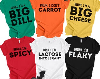 May include: A collection of colorful t-shirts with humorous phrases in black text. The shirts are green, orange, yellow, red, white, and black. Phrases include "Bruh, I'm a Big Dill," "Bruh, I don't Carrot," and "Bruh, I'm Flaky."