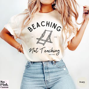 Comfort Colors Shirt with deck chair illustration in the center, curved text above, script below - BEACHING Not Teaching #Retired Year Est. 2026
