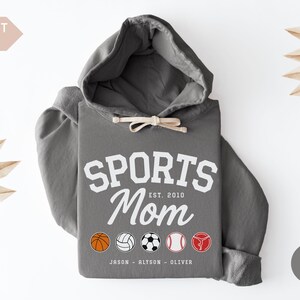 Multiple Sports Mom Hooded Sweatshirt with various sports ball icons, year established and kids names, mixture of college and cursive fonts