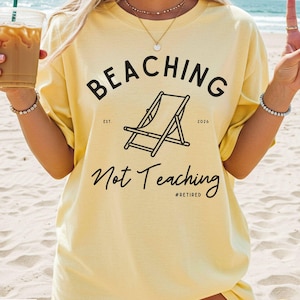 Comfort Colors Shirt with deck chair illustration in the center, curved text above, script below - BEACHING Not Teaching #Retired Year Est. 2026