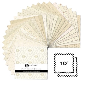 Könnte beinhalten: Eine Sammlung von 42 cremefarbenen Baumwollstoffquadraten von 25,4 cm x 25,4 cm, die aufgefächert sind, um verschiedene Muster zu zeigen. Der Stoff stammt aus der Snow Flurry-Kollektion von Laundry Basket Quilts. Das Andover-Logo ist sichtbar.