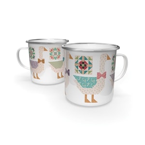 May include: Two white enamel mugs with silver rims. Each mug features a goose design with a bow tie and a patchwork quilt block. The geese are in a variety of colors, including beige, pink, and green.