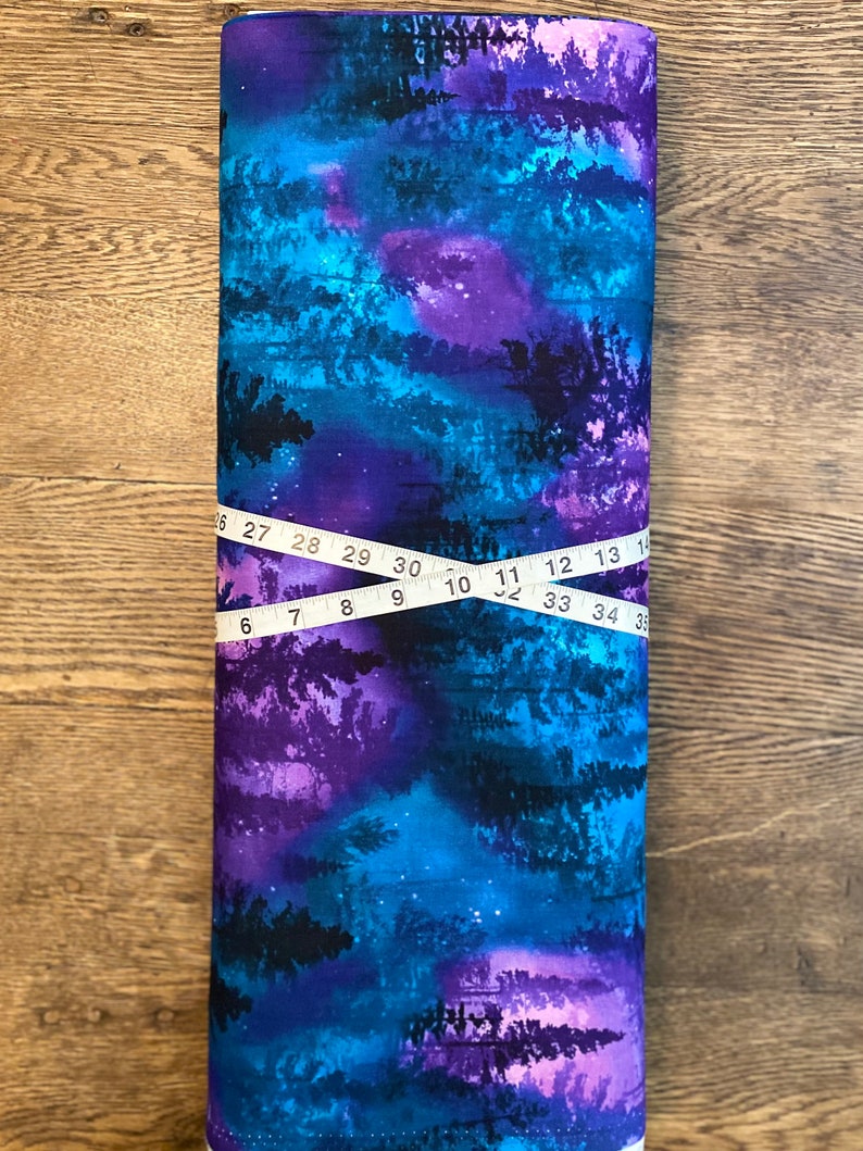 May include: A rolled fabric bolt with a vivid, abstract design in blue, purple, and black, reminiscent of a starry night or forest scene. A measuring tape shows a length of approximately 89 cm.