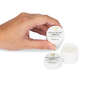 May include: A white plastic jar with a white label that says "HYALURONIC SERUM 5 SAMPLE SIZE" and the website address "LHBSKIN.COM".