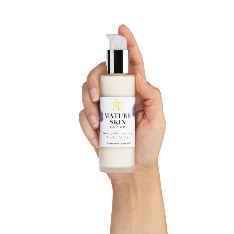 May include: A white bottle with a pump dispenser containing Mature Skin Serum. The bottle has a label with the text "Mature Skin Serum" and "Address Wrinkles, Firming, Lift & Collagen Building". The label also includes the text "Luxe Heavenly Bodies".